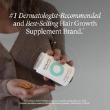 Woman holding Nutrafol Women’s Balance hair supplement capsules